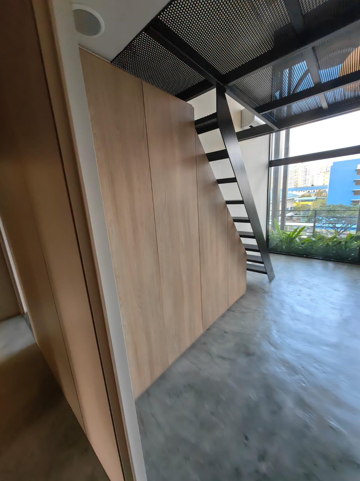 Office interior with full-height timber carpentry wall, black steel staircase and screed floor
